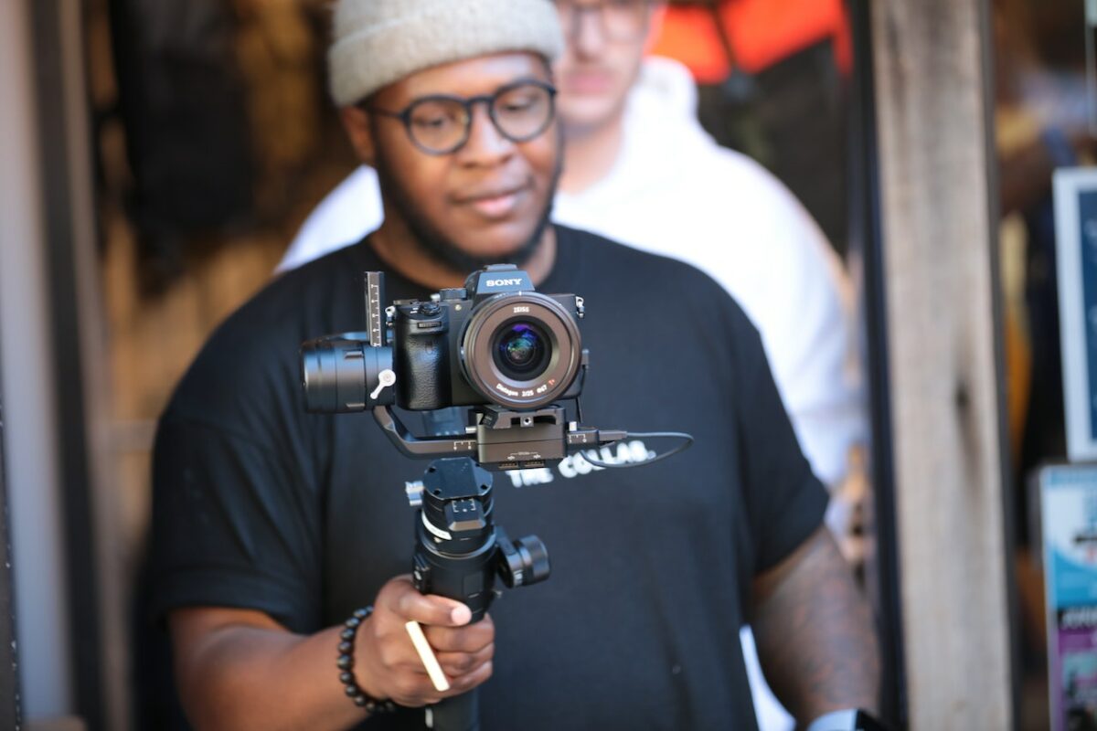 Un uomo che indossa una maglietta nera utilizza una sospensione cardanica nera e una fotocamera Sony
