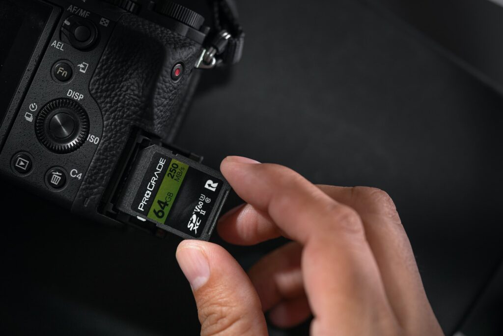 Een persoon die een zwarte geheugenkaart van 64 GB in een zwarte DSLR-camera plaatst