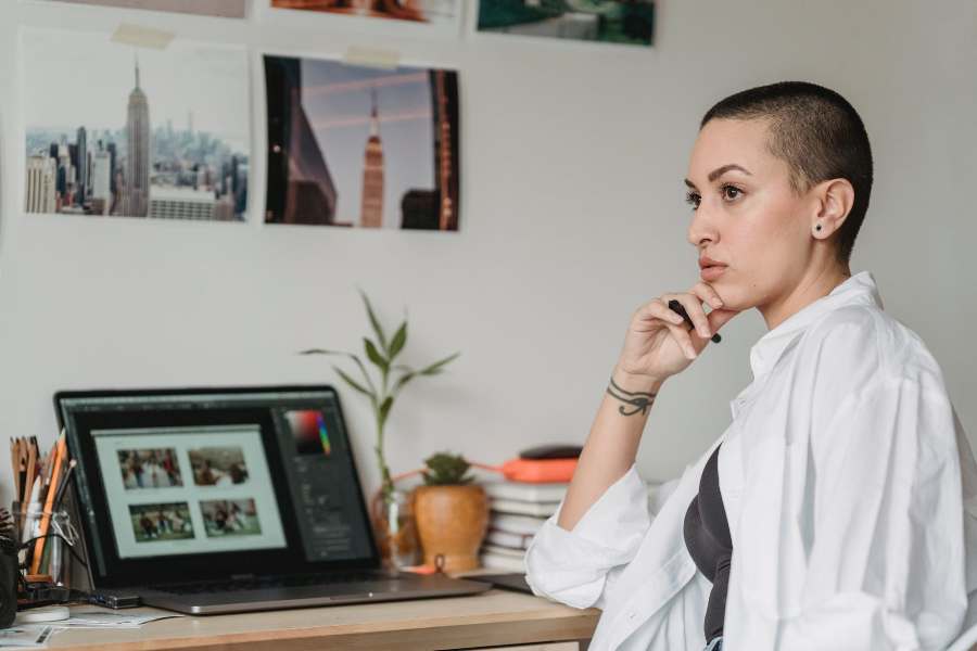 Mujer pensativa, sentada frente a su computadora portátil