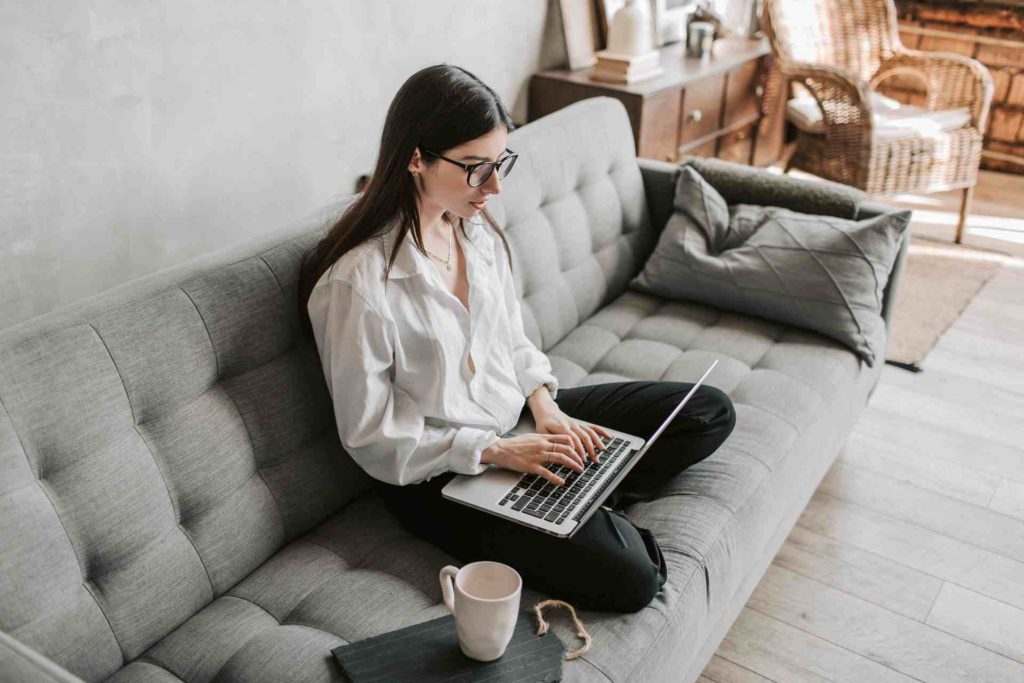Mujer usando una computadora portátil mientras está sentada en un sofá